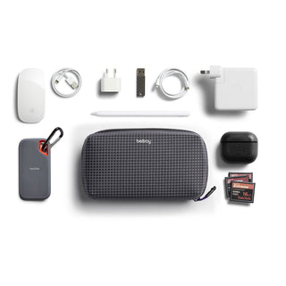 Bellroy Tech Kit in dark gray grid fabric with tech accessories and charging cables on white background