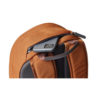 Bellroy Classic Backpack Second Edition in tan fabric with rear zippered pocket holding a smartphone