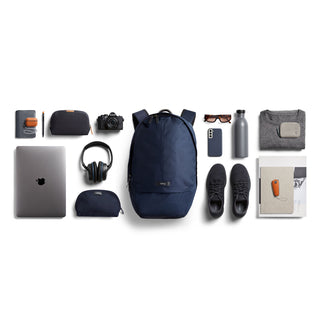 Bellroy Classic Backpack Plus Second Edition navy blue with everyday tech and travel essentials arranged around it