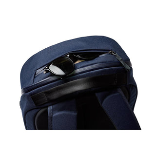 Bellroy Via Backpack in navy blue showing top zipper pocket with sunglasses inserted