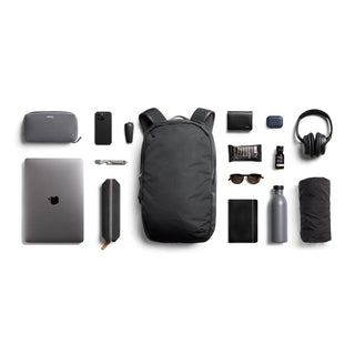 Bellroy Via Backpack in black surrounded by everyday tech and travel essentials on white background
