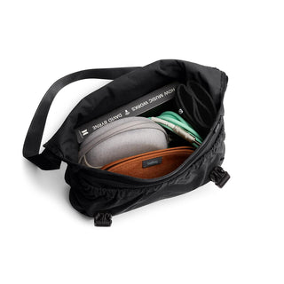 Bellroy Cinch Messenger Bag open to show organized interior with accessories and black recycled nylon exterior