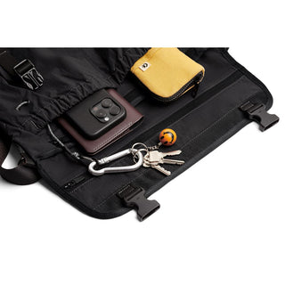 Bellroy Cinch Messenger Bag interior showing key clip, phone case, and yellow pouch on black fabric lining