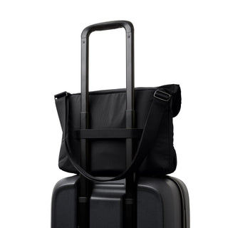 Bellroy Cinch Messenger Bag in black recycled nylon attached to suitcase handle from the back view