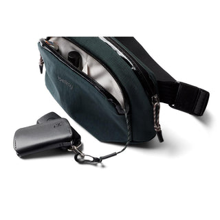 Bellroy Venture Hip Pack 1.5L in dark green showing open main compartment and attached key holder accessory