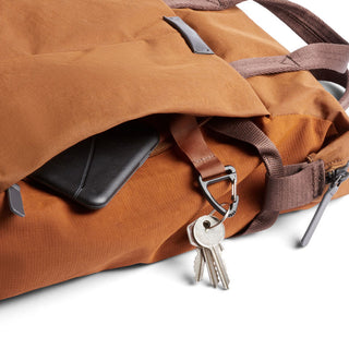 Bellroy Tokyo Totepack Compact in rust fabric with zipper pocket holding keys and phone close-up