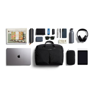 Bellroy Tokyo Work Bag flat lay with daily essentials including laptop, headphones, and sunglasses