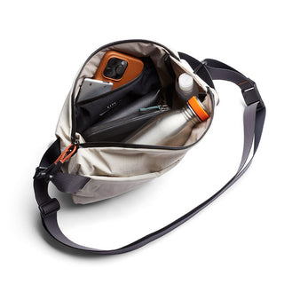 Bellroy Lite Sling crossbody bag open showing organized interior with bottle, wallet, and phone compartments