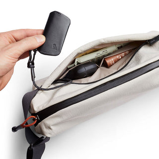 Bellroy Lite Sling crossbody bag in beige with zipper open showing organized inner compartments