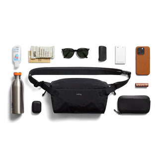 Bellroy Lite Sling black water-resistant crossbody bag with everyday essentials laid out nearby