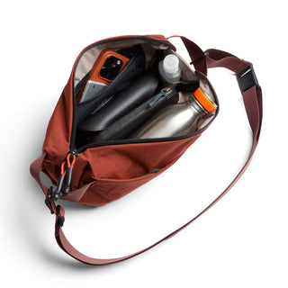 Bellroy Lite Sling crossbody bag in rust with organized interior holding daily essentials