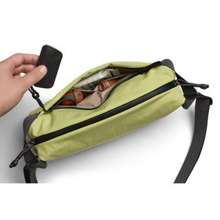 Bellroy Lite Sling in green with black strap, showing organized interior holding personal items