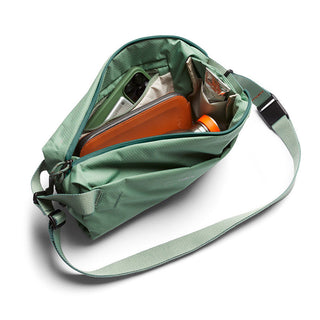 Bellroy Lite Sling in green showing organized interior compartments with tech accessories and wallet inside