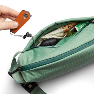 Bellroy Lite Sling in green with water-resistant fabric showing organized interior and hand holding key organizer