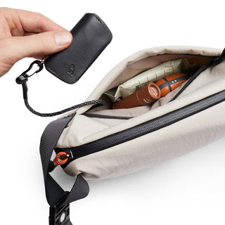 Bellroy Lite Sling Mini in beige showing compact interior with black key holder attached to zipper pull