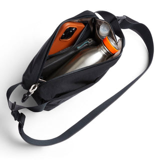 Bellroy Lite Sling Mini black crossbody bag with water bottle and phone inside, top view