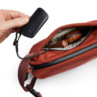 Bellroy Lite Sling Mini in rust red with accessible interior and attachable black key case
