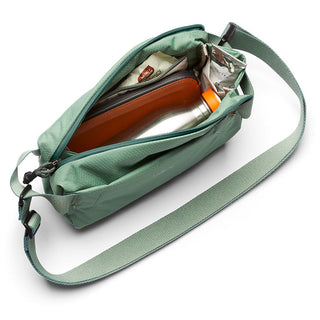 Bellroy Lite Sling Mini in green showing interior pockets with water bottle and wallet inside