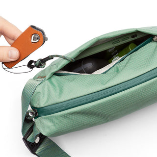 Bellroy Lite Sling Mini in green showing durable fabric and zipper pocket with tech accessories inside