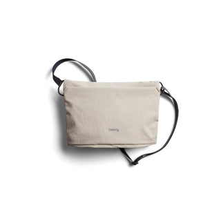 Bellroy Lite Sacoche in light beige recycled fabric with adjustable black crossbody strap flat lay view