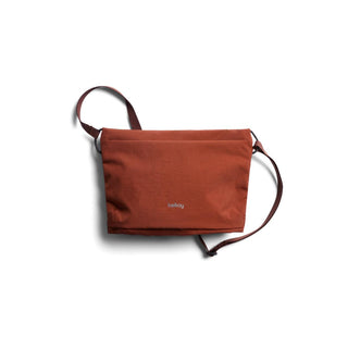Bellroy Lite Sacoche in rust red with adjustable strap and recycled fabric texture visible