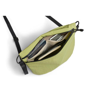 Bellroy Lite Sacoche in green showing organized inner compartments with various items inside
