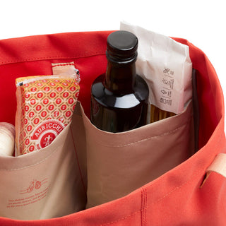 Bellroy Market Tote in red with inner organization pockets holding groceries and a glass bottle