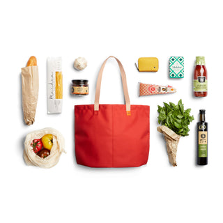 Bellroy Market Tote in red with natural leather handles, shown alongside groceries on white background