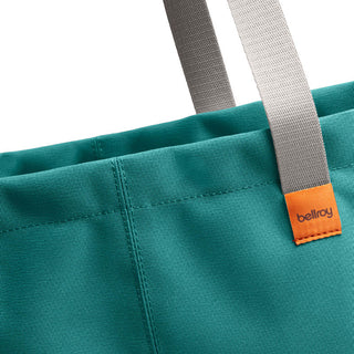 Bellroy Market Tote close-up showing turquoise recycled nylon fabric and grey handles with orange logo tag