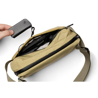 Bellroy Venture Sling 6L in tan showing spacious main compartment with black key pouch held nearby