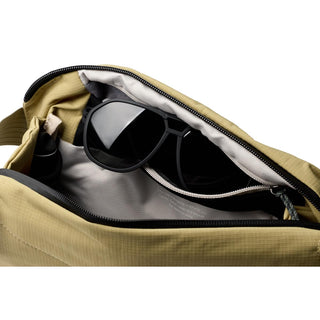 Bellroy Venture Sling 6L in tan fabric showing interior with black sunglasses inside pocket