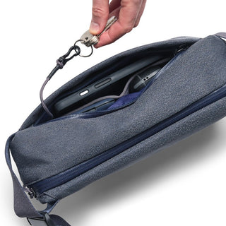 Bellroy Venture Sling 6L in navy blue fabric showing internal phone pocket and key clip in use