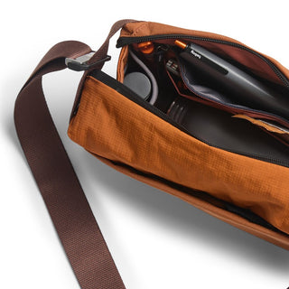 Bellroy Venture Sling 6L in rust orange showing organized interior with pens and tech accessories