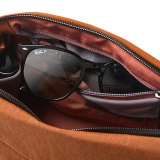 Bellroy Venture Sling 6L in rust brown showing spacious interior compartment with sunglasses inside