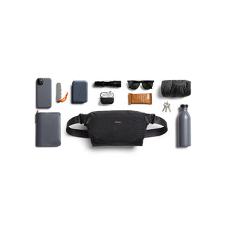 Bellroy Venture Sling 6L black nylon bag with everyday carry items neatly arranged around it on white background