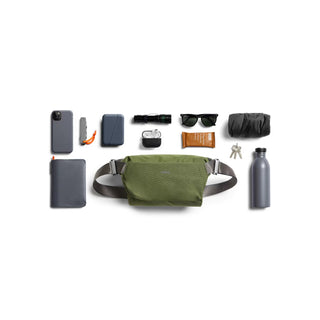 Bellroy Venture Sling 6L in olive green with adjustable strap and durable textured fabric displayed with essentials