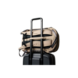 Bellroy Transit Workpack Pro 28L in tan secured on black suitcase handle with padded straps visible