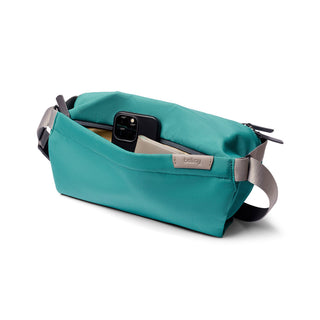 Bellroy Sling - 7L in teal water-resistant fabric with front pocket holding phone and wallet