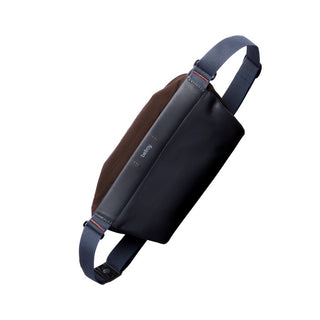 Bellroy Sling Mini Premium - 7L in black leather and dark fabric with adjustable blue strap shown at an angle