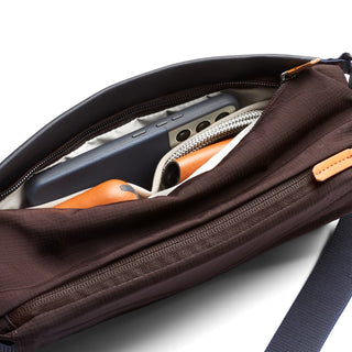 Bellroy Sling Mini Premium - 7L in brown fabric showing organized interior with phone and leather wallet inside