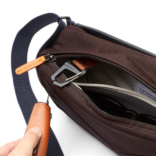 Bellroy Sling Mini Premium - 7L in dark brown with leather zipper pull and navy strap open to show interior compartments