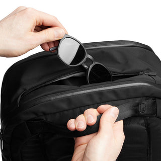 Bellroy Transit Backpack in black with water-resistant fabric and zippered front pocket holding sunglasses
