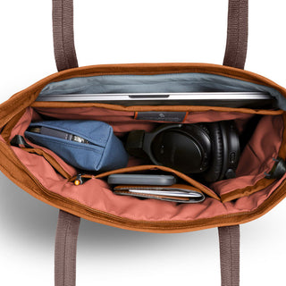 Bellroy Tokyo Tote Compact open, showing organized interior with laptop, blue pouch, headphones, and wallet compartments