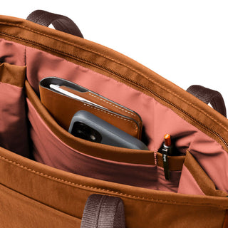 Bellroy Tokyo Tote Compact showing organized interior pockets with phone, notebook, and pen in brown fabric