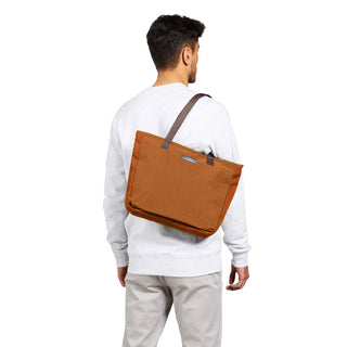 Bellroy Tokyo Tote Compact in burnt orange recycled fabric with leather strap worn over shoulder