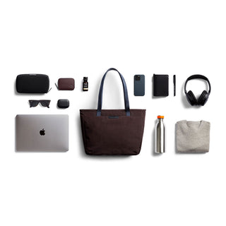 Bellroy Tokyo Tote Compact in dark fabric with navy handles surrounded by everyday tech and accessories