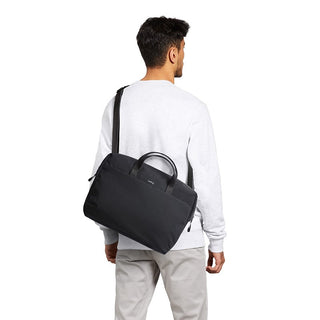 Man carrying black Bellroy Via Work Bag (Tech Briefcase) over shoulder with dual handles visible