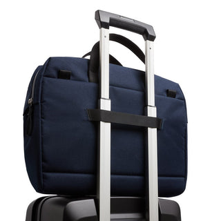 Bellroy Via Work Bag (Tech Briefcase) in navy blue securing to suitcase handle with fabric strap