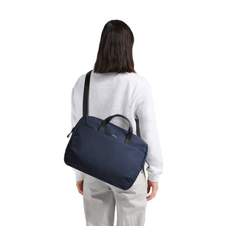 Person carrying navy Bellroy Via Work Bag (Tech Briefcase) with top handles and shoulder strap on back