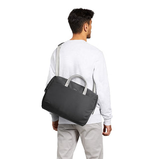 Man carrying black Bellroy Via Work Bag (Tech Briefcase) with grey handles over shoulder from rear angle